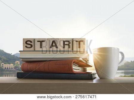 Wooden Blocks With The Word Start, Notebook, Books And Coffee On Table With Panoramic Landscape Back