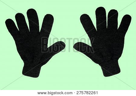 A Pair Of Grey Winter Knitted Gloves. Vertically. On A Green Background. The View From The Top. Isol