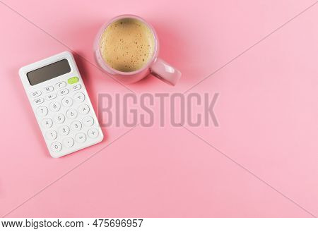 Top View Or Flat Lay Of White  Calculator And Pink Cup Of Coffee On Pink Background With Copy Space.