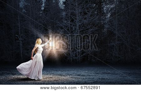 Young woman in white long dress walking in night wood