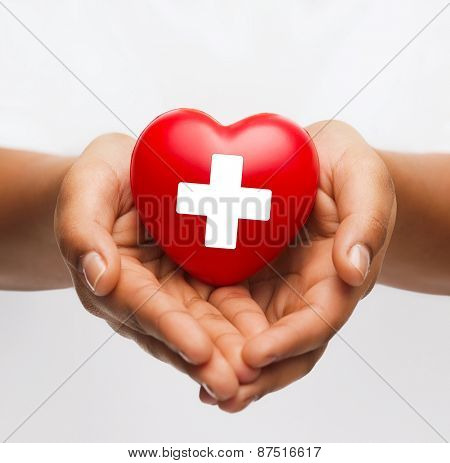 family health, charity and medicine concept - african american female hands holding red heart with cross sign