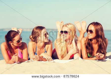 summer vacation, holidays, travel and people concept - group of smiling young women in sunglasses lying on beach