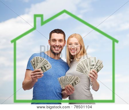 love, home, people and family concept - smiling couple holding dollar cash money over green house and blue sky background