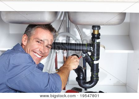 Young plumber fixing a sink at kitchen.