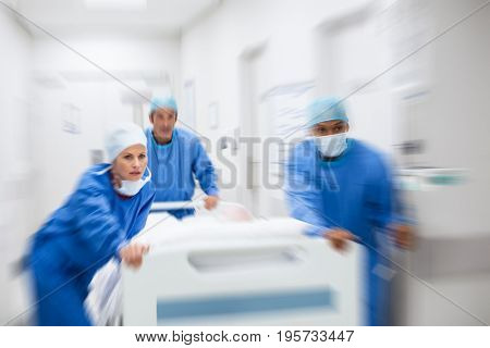 Nurse and doctor in a hurry taking patient to operation theatre. Patient on hospital bed pushed from surgeon to emergency theatre. Team of doctors and surgeon rushing patient.