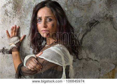 Homeless young woman dressed in rags in a derelict building