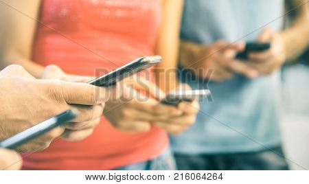 Multicultural friends using smartphone outdoors - People hands addicted by mobile smart phone - Technology concept with connected men and women - Shallow depth of field on bright vintage filtered tone