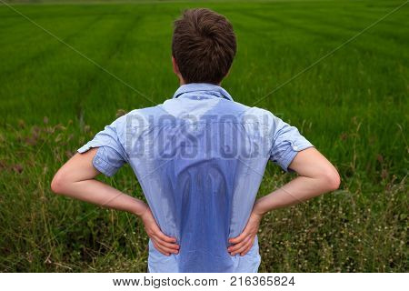 Man with hyperhidrosis sweating very badly under armpit in blue shirt because of hot weather. Travelling in asia thailand with backpacker