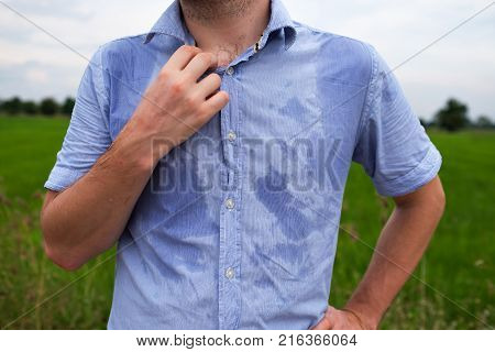 Man with hyperhidrosis sweating very badly under armpit in blue shirt because of hot weather. Travelling in asia thailand with backpacker