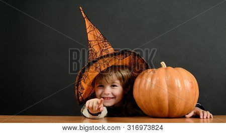 Little Boy In Witch Hat With Halloween Pumpkin Pointing To You. Trick Or Treat. Preparation Hallowee