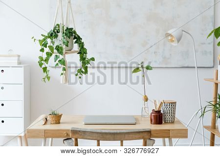 Stylish And Boho Home Interior Of Open Work Space With Wooden Desk, Chair, Lamp, Laptop And White Sh