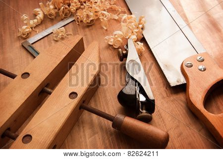 Wood working desk near the window with incandescent lighting, Wood working tools and wood shavings. 