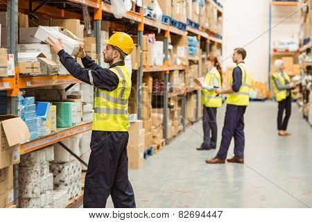 Warehouse worker taking package in the shelf in a large warehouse in a large warehouse