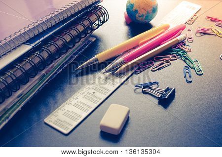 School supplies on blackboard background. Back to school concept with stationery. Notebook stack pens and pencil. Schoolchild and student studies accessories. Back to school concept. Toned image.