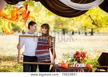 Beautiful Young Pregnant Couple Having Picnic In Autumn Park. Happy Family Outdoor.