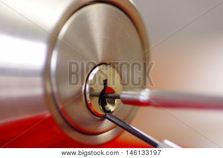 Closeup hands of locksmith using metal pick tools to open locked door.