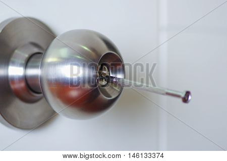 Closeup hands of locksmith using metal pick tools to open locked door.