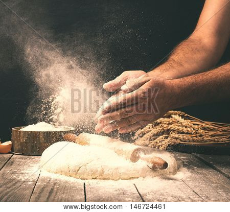 Man preparing bread dough on wooden table in a bakery close up