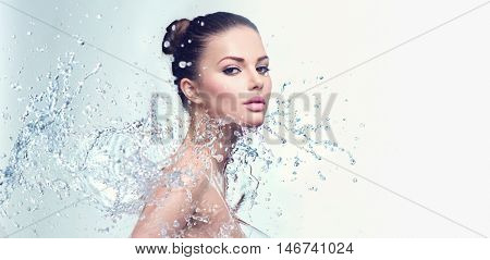 Beautiful Model Spa Woman with splashes of water. Beautiful Smiling girl under splash of water with fresh skin over blue background. Skin care, Cleansing and moisturizing concept. Beauty face