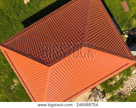 House With An Orange Roof Made Of Metal, Top View. Metallic Profile Painted Corrugated On The Roof