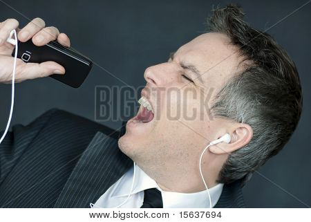 Businessman Wearing Headphones Sings Into Cell Phone