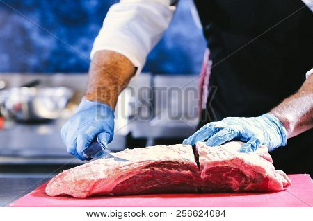 Butcher cutting pork meat on kitchen, Chef cutting fresh raw meat on board, Close up of butcher cutt