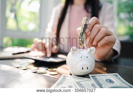 Closeup Of Business Woman Hand Putting Money Into Piggy Bank For Saving Money. Saving Money And Fina