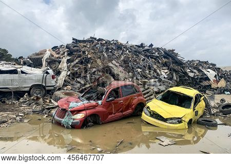 Broken Car In A Junkyard, Car Scrap, Crushed Corroded Old Automobiles Stacked In Scrapyard In Puddle