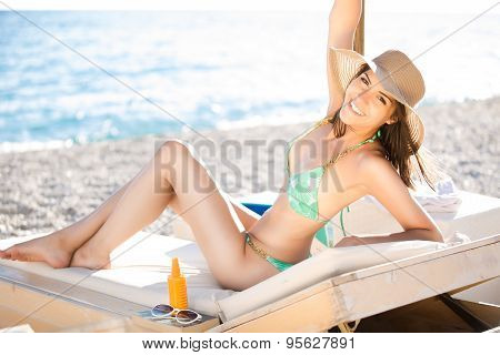 Smiling beautiful woman sunbathing in a bikini on a beach at tropical travel resort,enjoying summer