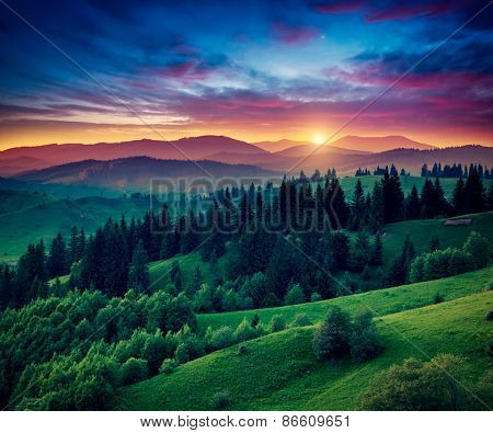 Green hills glowing by warm sunlight at twilight. Dramatic scene. Colorful sky, red clouds. Carpathian, Ukraine, Europe. Beauty world.