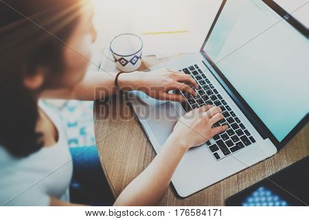 Closeup of woman surfing web at living room on modern computer while sitting at the wooden table.Female hands typing on laptop keyboard.Concept of young modern people using mobile devices at home