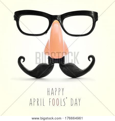 fake eyeglasses, nose and mustache and the text happy april fools day in a beige background, with a retro effect