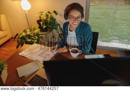 Smiling Afro American Woman Interior Designer In Headphones Works With Documents In Home Office