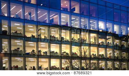 LONDON, UK - DECEMBER 19, 2014: Office block with lots of lit up windows and late office workers ins