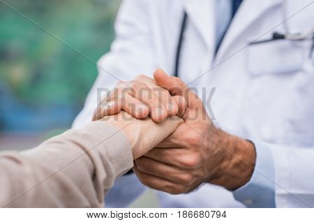 Close up of doctor hand reassuring her female patient at hospital. Closeup hands of medical doctor carefully holding patient's hands. Kind doctor giving real support for patient. 