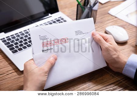 Person Holding Final Notice Invoice In Envelope