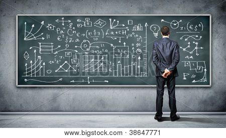 Business person standing against the blackboard with a lot of data written on it