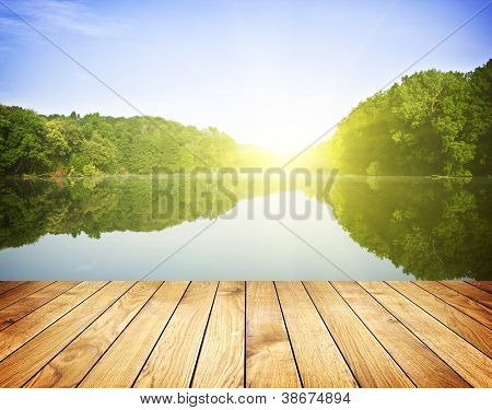 Sunset forest lake ja puulautaan tausta