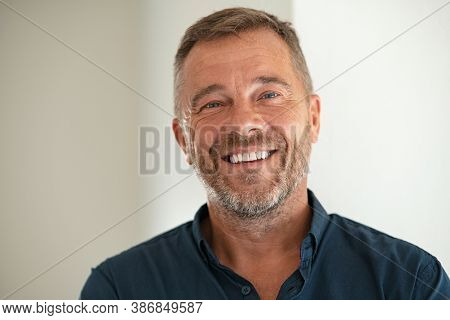 Handsome businessman smiling and looking at camera. Portrait of carefree mature man with copy space. Successful mid adult business man laughing.