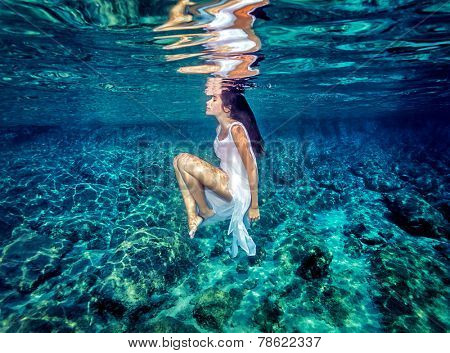 Beautiful dance underwater, gorgeous sportive woman wearing long white dress, dive to clear blue sea, zen balance and meditation concept