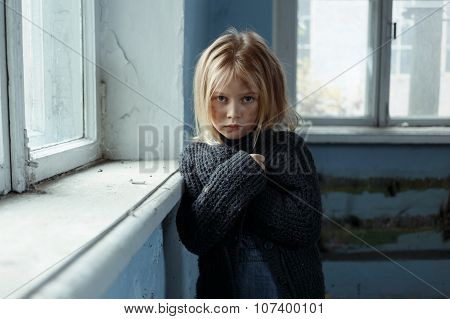 Depressed poot girl standing near window