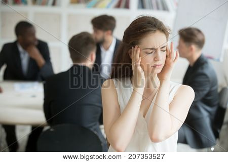 Stressed young female corporate employee having migraine at unproductive briefing. Business woman got headache from stressful meeting, coworkers not collaborating. Female executive sick from stress.