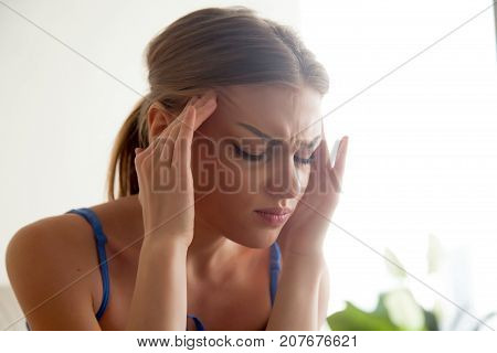 Strong headache concept, young woman massaging temples with eyes closed, suffering from chronic migraine, stressed teenager experiencing sudden panic attack, feeling pain, head shot portrait