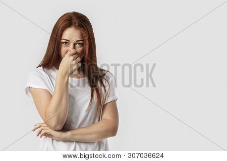 Young Redhead European Female Isolated On White Background Dressed In White T-shirt, Covering Nose W