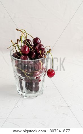 Ripe Fresh Red Sweet Cherry In A Glass Beaker On A White Concrete Background