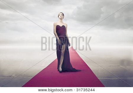 Belle femme élégante, marchant sur le tapis rouge