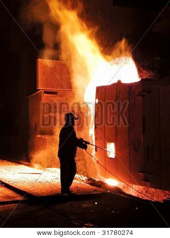 A steel worker takes a sample at steel company