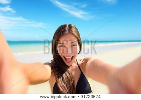 Selfie fun woman taking photo at beach vacation. Summer holiday girl happy at smartphone camera taking self-portrait on her travel vacations on pristine paradise beach.