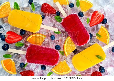 refreshing fruit popsicle lollies on ice background with berries and peppermint.