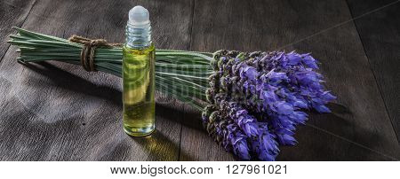 fresh lavender flowers and essential oil as natural aromatherapy for headache and migraine relief on old wooden background